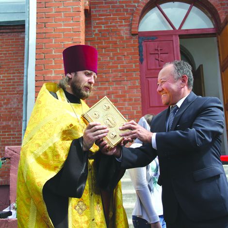 Глава Любинского района А.К. Ракимжанов вручает Евангелие отцу Владимиру.